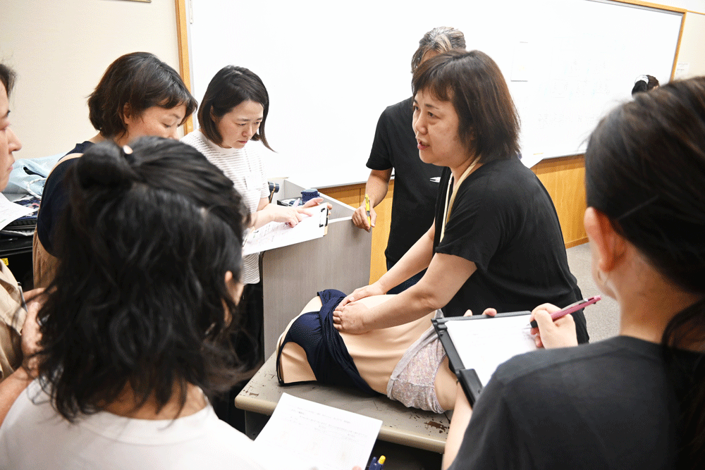 経験談も踏まえレオポルド触診法を解説する井上氏。子宮底部を包み込むようにし胎児の向きを探る